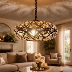 Puede incluir: Una lámpara colgante decorativa de forma ovalada con un patrón perforado detallado. La cálida luz ambiental proyecta intrincadas sombras en el techo. Ideal para la decoración del hogar.