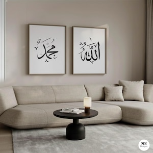 Puede incluir: Dos impresiones artísticas enmarcadas con caligrafía árabe cuelgan sobre un sofá beige. Las impresiones presentan escritura negra sobre fondo blanco, una que dice "Muhammad" y la otra "Allah". Una pequeña mesa negra y una lámpara están frente al sofá.
