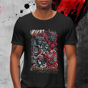 May include: Black t-shirt featuring a graphic of stylized demons in red, gray, and black. The design includes the text "YOKAI" at the top and "Demons of the Inner Mind" at the bottom. The artwork has a detailed, illustrative style.