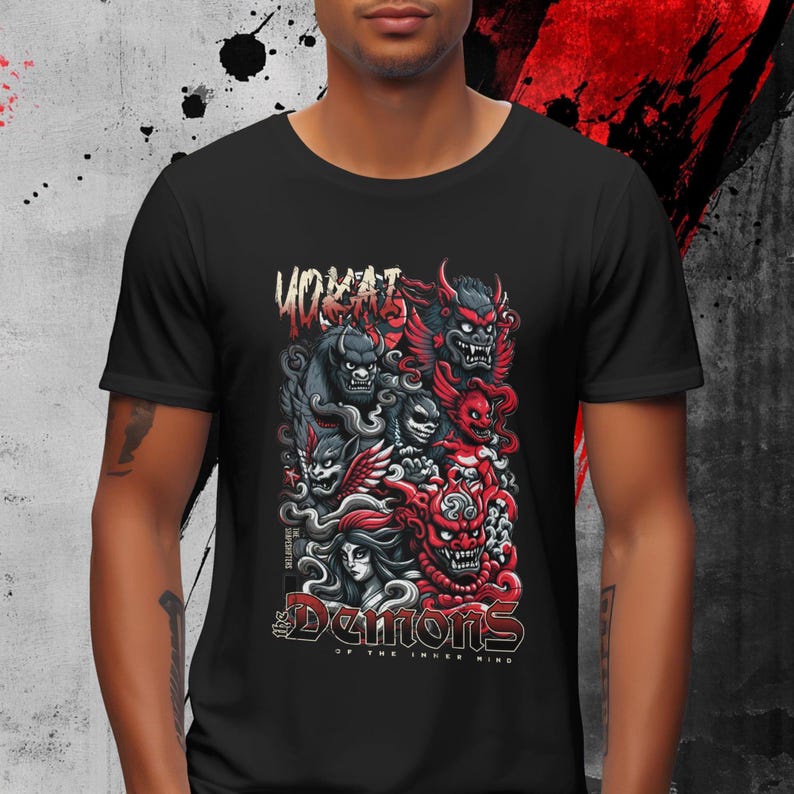 May include: Black t-shirt featuring a graphic of stylized demons in red, gray, and black. The design includes the text "YOKAI" at the top and "Demons of the Inner Mind" at the bottom. The artwork has a detailed, illustrative style.