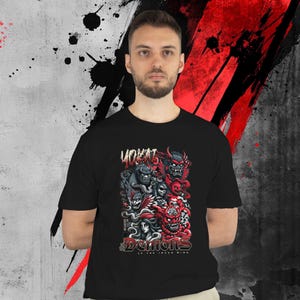 May include: Black t-shirt featuring a graphic of demons in red, gray, and black. The text "VOKAT" is above the graphic, and "DEMONS OF THE INNER MIND" is below. The shirt is worn by a person.