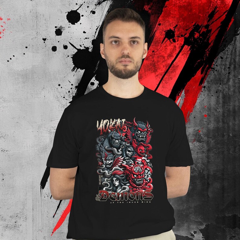 May include: Black t-shirt featuring a graphic of demons in red, gray, and black. The text "VOKAT" is above the graphic, and "DEMONS OF THE INNER MIND" is below. The shirt is worn by a person.