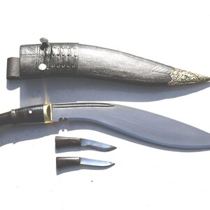 May include: A traditional Kukri knife with a curved blade, black handle, and a decorative sheath. Two smaller knives are also included. The blade is approximately 12 inches long.