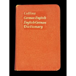 May include: A small, orange Collins German-English English-German Dictionary. The book has a rectangular shape with rounded corners and a white label with black text. The cover has a textured appearance.