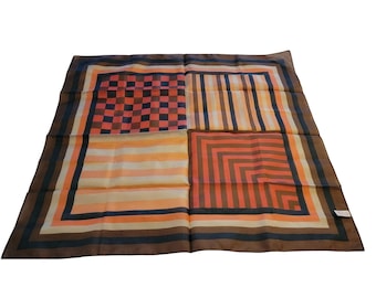 Könnte beinhalten: Ein quadratisches Seidentuch mit einem geometrischen Muster in Braun-, Orange-, Blau- und Pfirsichtönen. Der Schal ist in vier Abschnitte unterteilt, die jeweils ein anderes Design aufweisen, darunter Streifen, ein Schachbrettmuster und ein geometrisches Quadrat.