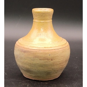 May include: A handcrafted, small, ceramic vase with a narrow neck and rounded body. The vase has a light yellow-brown color with subtle green and pink hues. The surface has horizontal ridges and a textured appearance, suggesting a rustic aesthetic.