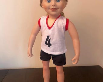 Puede incluir: Una muñeca con un jersey de baloncesto blanco y rojo con el número "4" en la parte delantera, pantalones cortos negros y cabello rubio.