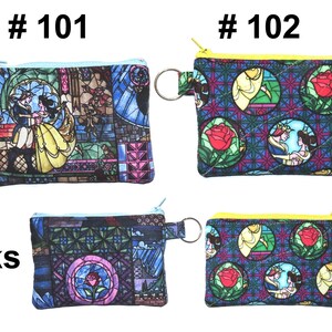 May include: Four small, rectangular coin purses with zipper closures and key rings. Two purses feature a stained-glass design with a couple dancing, while the other two have a rose and princess design. The purses are in shades of blue, yellow, and pink.