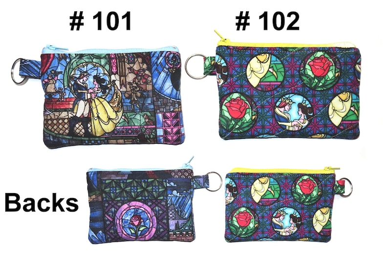 May include: Four small, rectangular coin purses with zipper closures and key rings. Two purses feature a stained-glass design with a couple dancing, while the other two have a rose and princess design. The purses are in shades of blue, yellow, and pink.