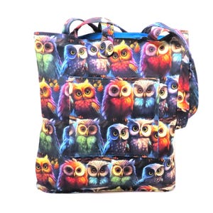 May include: A tote bag featuring a repeating pattern of colorful owls. The owls are depicted in various colors, including red, blue, green, and yellow, with detailed feather patterns. The bag has a pocket and handles.