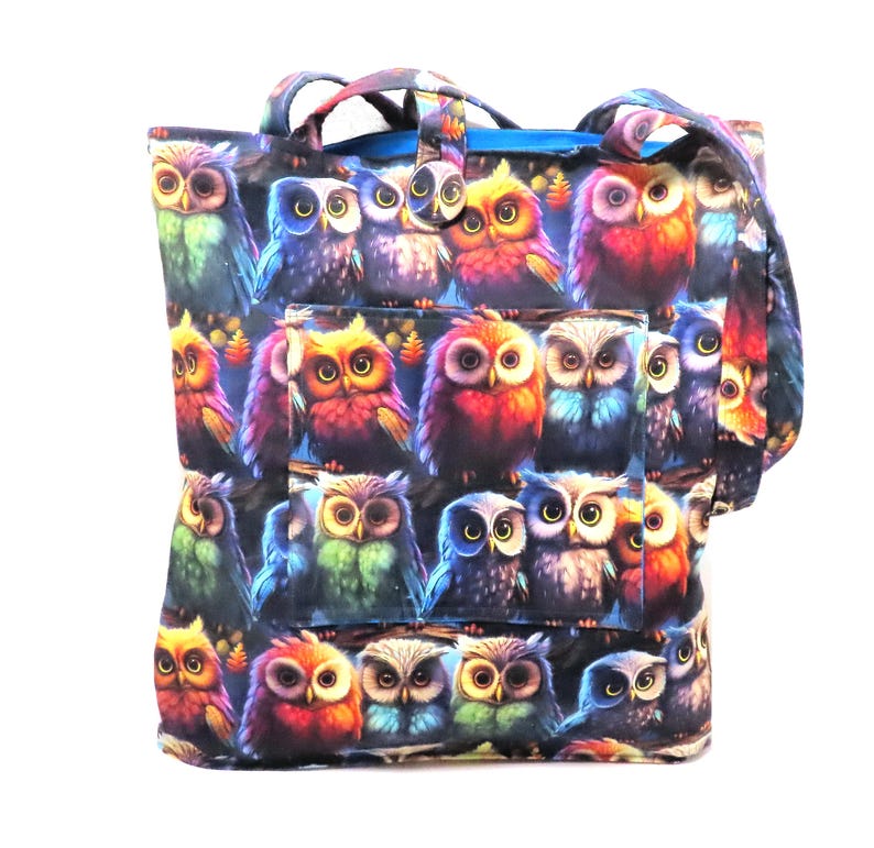 May include: A tote bag featuring a repeating pattern of colorful owls. The owls are depicted in various colors, including red, blue, green, and yellow, with detailed feather patterns. The bag has a pocket and handles.