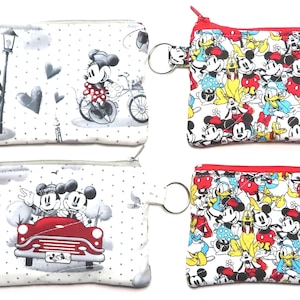 May include: Four small zippered coin purses. Two purses feature Mickey Mouse in Paris scenes, and two feature Mickey, Minnie, and Donald Duck. Each purse has a key ring attached.
