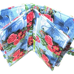 May include: A blue and pink floral fabric wallet with a flap closure and a wrist strap. The wallet has multiple compartments for cards and cash.