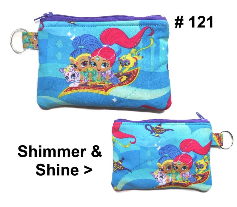 May include: Two small, blue, quilted coin purses with a zipper closure and a key ring. The purses feature a colorful graphic of characters from Shimmer and Shine. The text "Shimmer & Shine >" is printed on the image.