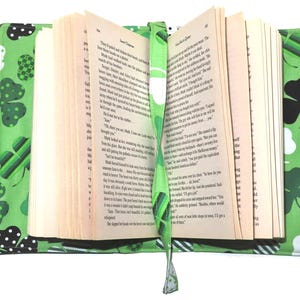 May include: A green book cover with a St. Patrick's Day theme, featuring shamrocks and white polka dots. The cover has handles and a matching bookmark. The book is open, revealing the pages.