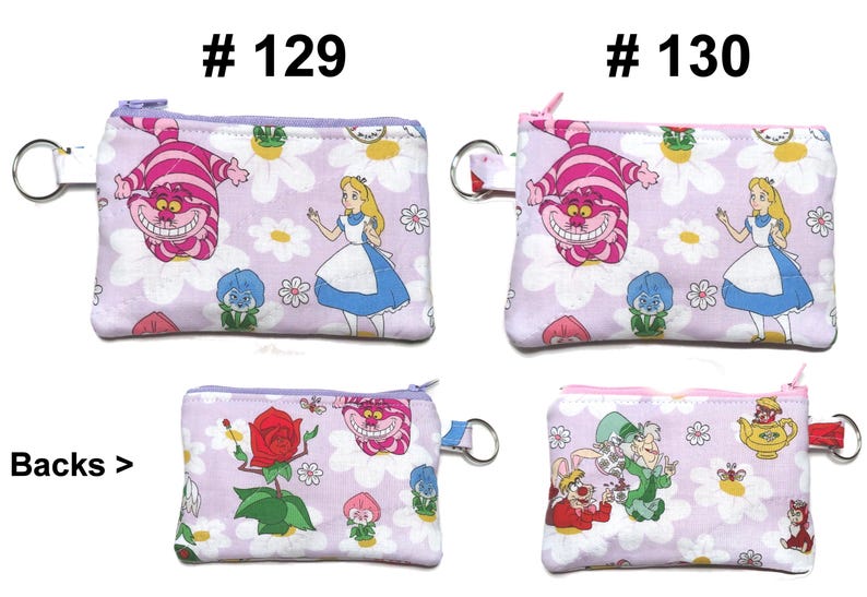 May include: Four small, rectangular coin purses with zipper closures and key rings. The purses feature illustrations from Alice in Wonderland, including the Cheshire Cat, Alice, and other characters, set against a floral background. The text "# 129" and "# 130" is visible.