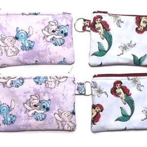 May include: Four small zippered pouches. Two pouches feature a Stitch and Angel design on a lavender background. The other two pouches have a Little Mermaid design on a white background. Each pouch has a key ring.