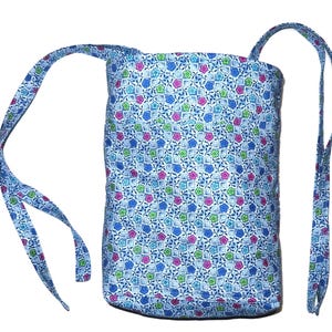 May include: A blue and white fabric bag with a floral pattern. The bag has two long straps that can be worn over the shoulder.