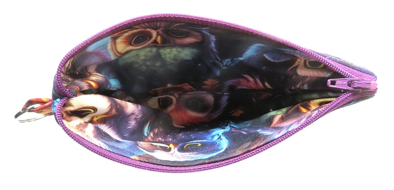 May include: A purple zippered pouch with a vibrant owl print interior. The pouch features a key ring attachment and a contrasting purple zipper. The owl design includes shades of blue, purple, and brown.