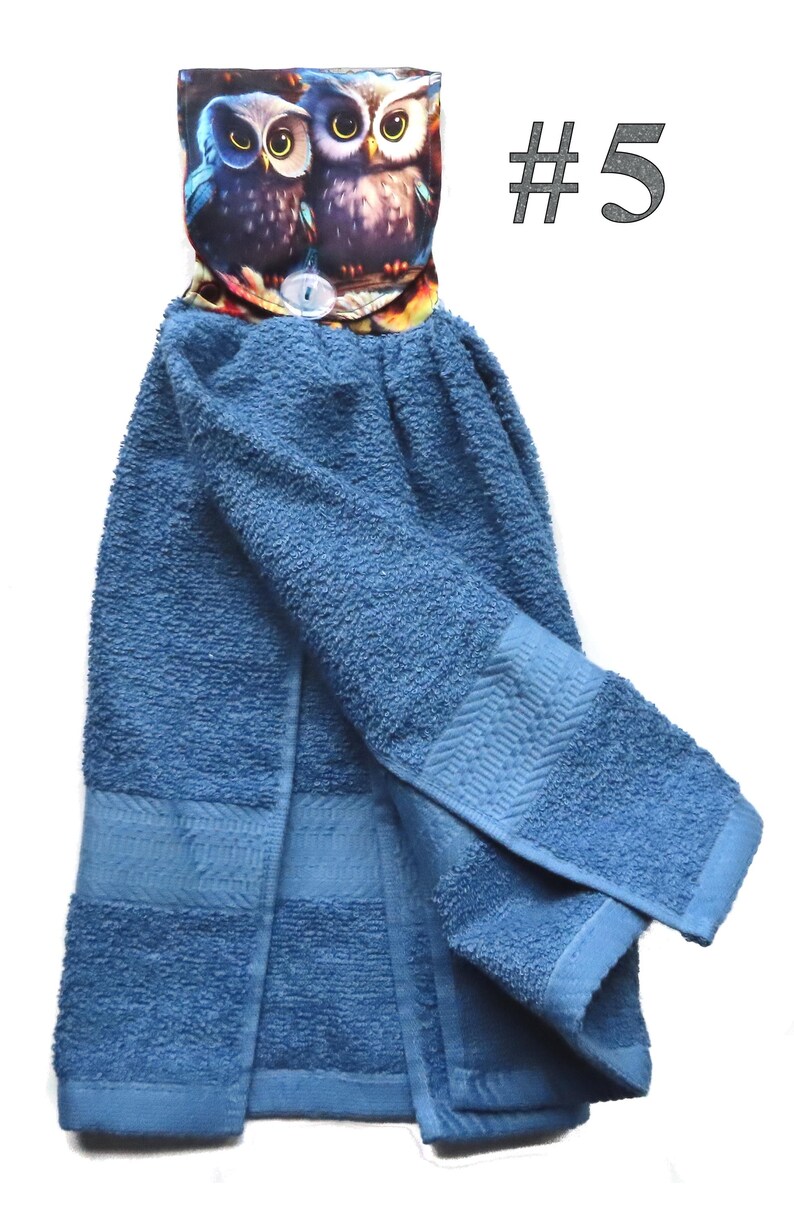 May include: Blue kitchen towel with an owl-themed top. The top features two owls with large yellow eyes. The towel is a solid blue color with a textured surface. The number "#5" is printed in the upper right corner.