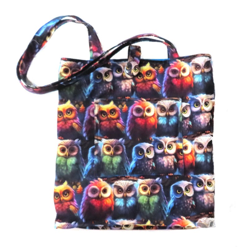 May include: A tote bag featuring a colorful owl pattern. The bag has a dark background with multiple owls in various colors, including red, blue, and green. The handles and trim have a coordinating pattern.
