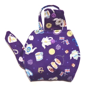 May include: A purple tea cozy with a teapot shape. The cozy is covered in a pattern of teacups, teapots, and British flags. The handle is white. The cozy is designed to keep tea warm.