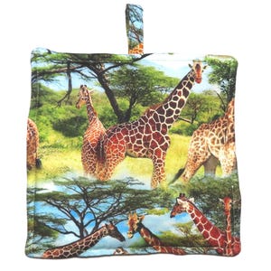 May include: Square pot holder featuring a vibrant print of giraffes in a savanna landscape. The design includes multiple giraffes with their distinctive brown and tan patterned coats, set against a backdrop of trees, grass, and a blue sky. It has a small loop for hanging.