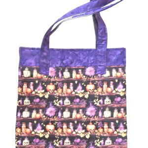 May include: A rectangular tote bag featuring a repeating pattern of shelves filled with various glass bottles, jars, and skulls in shades of purple, orange, and white against a black background, finished with solid purple fabric handles and trim.