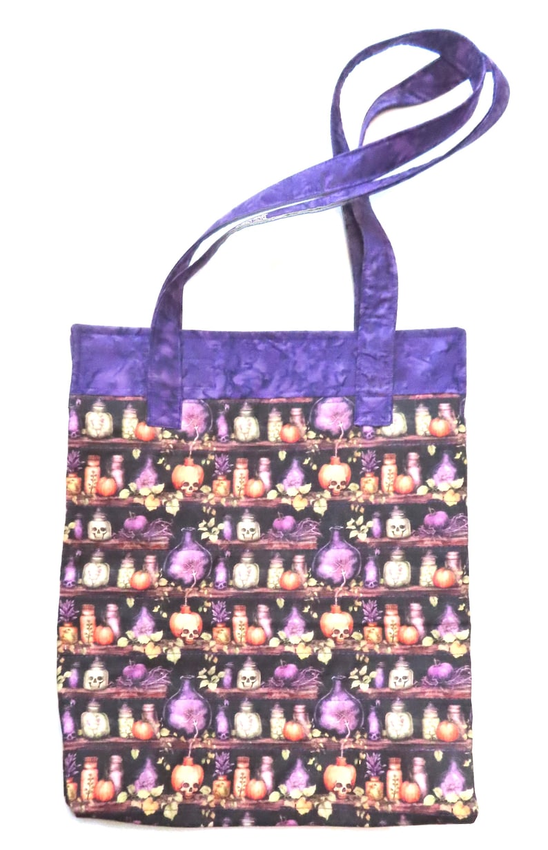 May include: A rectangular tote bag featuring a repeating pattern of shelves filled with various glass bottles, jars, and skulls in shades of purple, orange, and white against a black background, finished with solid purple fabric handles and trim.