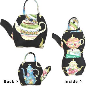 May include: Black teapot-shaped fabric bag with a handle and spout. The bag features a colorful floral teapot design on the front and back, with a button closure. The inside of the bag has a pocket.