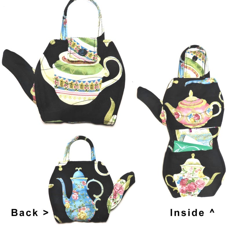 May include: Black teapot-shaped fabric bag with a handle and spout. The bag features a colorful floral teapot design on the front and back, with a button closure. The inside of the bag has a pocket.