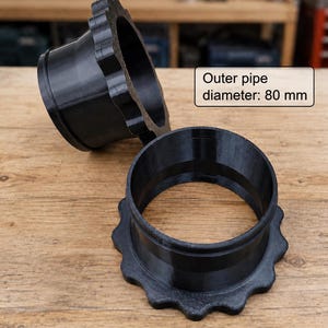Könnte beinhalten: Zwei schwarze, zylindrische, 3D-gedruckte Rohradapter mit einem gezackten, zahnradartigen Flansch an einem Ende. Ein Textfeld gibt einen äußeren Rohrdurchmesser von 80 mm an. Die Komponenten weisen eine glatte, geschichtete Oberfläche auf.