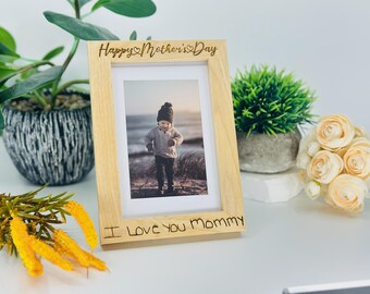 May include: A wooden photo frame with the text "Happy Mother's Day" and "I Love You Mommy" engraved on it. The frame contains a photo of a child.