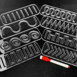 May include: Set of seven clear plastic stencils with different line patterns, including straight lines, zigzags, spirals, and arrows. A red and white marker is included.