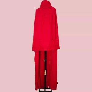 May include: A long, red cape with a hood. The cape is draped over a mannequin and is made of a soft, flowing fabric.