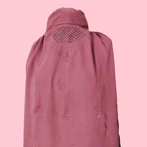 May include: A long, pink garment with a mesh panel over the face and embroidered details. The garment is worn by a person, but the person's face is not visible.
