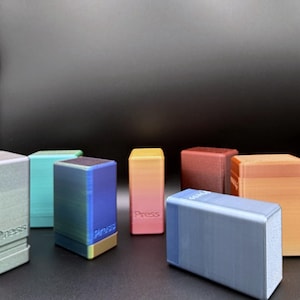 May include: A selection of multi-coloured rectangular blocks, some with the word "Press" printed on them. The blocks display a range of gradient colours and are arranged on a dark surface, showcasing a variety of hues.