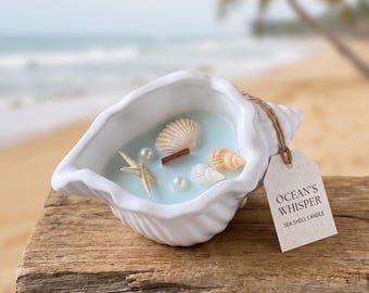 May include: A white ceramic seashell-shaped candle filled with light blue wax. The candle features embedded decorative elements including a small starfish, various miniature seashells, two white pearls, and a wooden wick. A tag reads OCEAN'S WHISPER SEA SHELL CANDLE.
