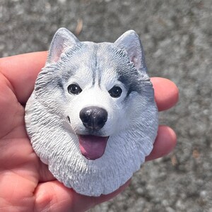 May include: A white and grey husky dog figurine with a pink tongue sticking out. The figurine is made of a realistic material and has a detailed face.