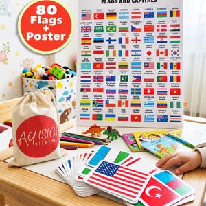 Puede incluir: Un conjunto de materiales educativos que incluye un póster titulado FLAGS AND CAPITALS con 80 banderas nacionales, un mazo de tarjetas de banderas, una bolsa de tela beige con un logo circular rojo, lápices de colores y dos figuras de dinosaurios.