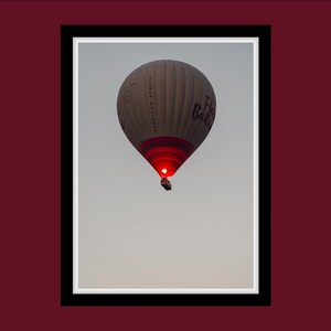 May include: A white hot air balloon with red and white stripes and the text "Flower Balloons" and "Fly Balloon" in black. The balloon is in the air against a light blue sky.
