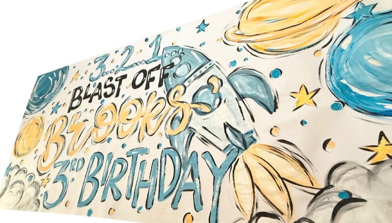 May include: A white banner with a blue and yellow space-themed design. It says "Blast Off Brookes 3rd Birthday" with a rocket ship and planets.