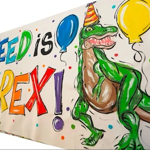 May include: A colorful banner with the text "Reed is 3 Rex!" in rainbow colors. A green dinosaur with a party hat is drawn on the banner with colorful balloons.