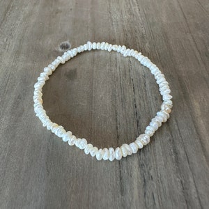 May include: A white pearl necklace made of small, irregular shaped pearls.