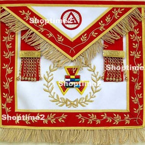 May include: A white, red, and gold Masonic apron with intricate embroidery. The apron features a red border with gold fringe, gold chain accents, and a central emblem. The text "Shoptime2" is visible on the apron.