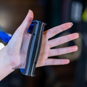 Pode incluir: Uma pega de exerc&iacute;cio preta e azul com uma pega texturizada. A pega tem um furo no lado.