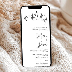 Op de afbeelding: Een smartphone toont een uitnodiging voor een hernieuwing van de geloften. De tekst luidt "we still do" met een hart, gevolgd door details voor de hernieuwing van de geloften van Selena en Dean. De uitnodiging bevat datum, tijd en locatie: The Monrose Estate, Laketown, NC.