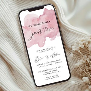 Może przedstawiać: Smartfon wyświetla zaproszenie ślubne z różowym akwarelowym wzorem. Tekst brzmi „NOTHING FANCY just love” i zawiera szczegóły wydarzenia: datę, godzinę, miejsce i informacje RSVP. Zaproszenie jest na białym tle.