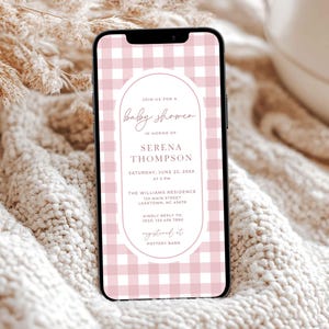 Può includere: Uno smartphone mostra un invito per un baby shower. L'invito presenta uno sfondo a quadretti rosa e una cornice ovale con i dettagli del baby shower di Serena Thompson. Il telefono è appoggiato su uno sfondo strutturato e neutro.