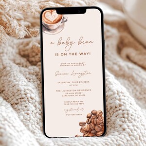 Può includere: Un invito digitale per una festa di nascita con un'illustrazione di una tazza di caffè e chicchi di caffè. L'invito recita "a baby bean is on the way!" e include il nome Serena Livingston, la data e l'ora della festa, la posizione e le informazioni di RSVP. L'invito è progettato con uno sfondo marrone chiaro e testo marrone.